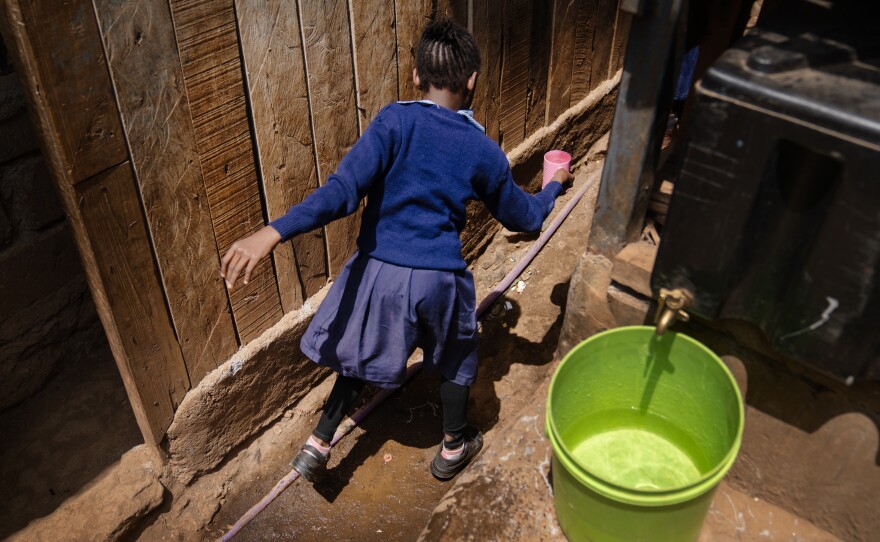A student at Saint Juliet's primary school in Kibera, Nairobi's largest slum, takes a cup of water back to the classroom with her. The school's water comes from the atmospheric water generator from a nonprofit group called Majik Water<strong>.</strong>