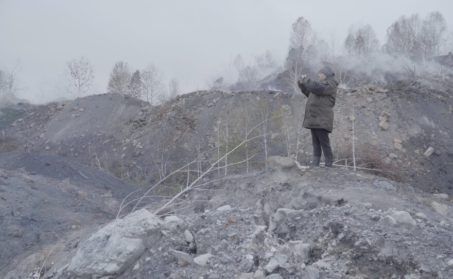 Protagonist Natalia Zubkova captures the burning ground on her phone.
