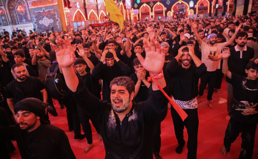 A pilgrim raises his hands and chants amid the crowds during mourning rituals inside the Imam Hussein Shrine in Karbala during the Arbaeen commemoration.
