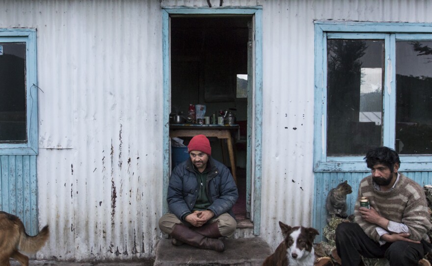 Outside the ranch kitchen, Juan Luis and work companion Luis Enrique (right) rest after hauling firewood.