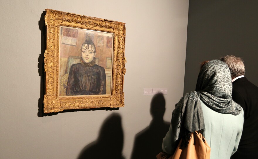 Visitors look at the painting titled "Girl with Lovelock" by French artist Henri de Toulouse-Lautrec at the opening of the exhibition.