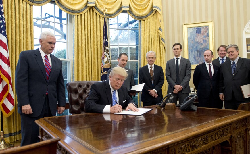 President Trump signs the executive orders in the Oval Office on Monday, including a withdrawal from the Trans-Pacific Partnership trade deal.