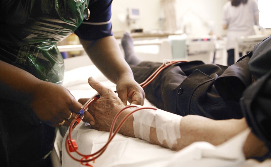 A nurse adjusts the position of a patient's arm during dialysis treatment. The treatment requires trained staff that weren't readily available in the aftermath of Hurricane Sandy.