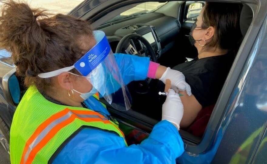 A woman receives a COVID-19 vaccine while sitting in her vehicle on Jan. 23, 2021. Imperial County held a drive-up clinic outside its administrative offices for in-home support service providers.