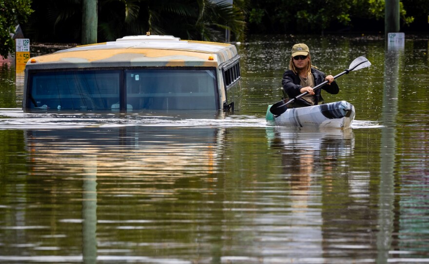 A man paddles his kayak next to a submerged bus on a flooded street in the town of Milton in suburban Brisbane, Australia, on Monday.