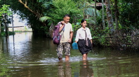A school girl and her father wade through floodwaters in Alengmora village in Jorhat, India, Monday, Aug. 10, 2026.