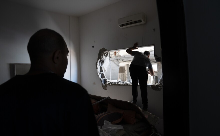 Noor Damaj (left) looks on as a fellow Jenin resident surveys the mosque destruction through a bedroom window at his home.