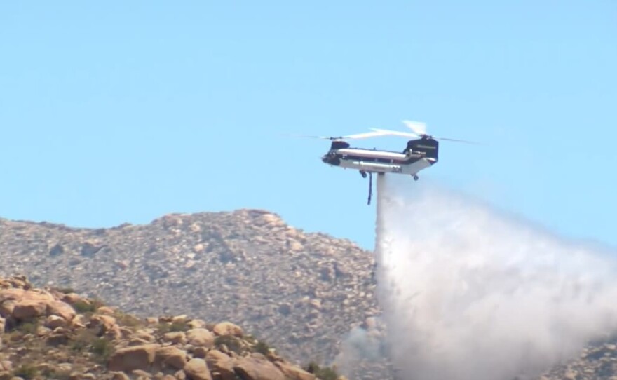 A helicopter drops water on the McCain fire in southeast San Diego County, July 2, 2024