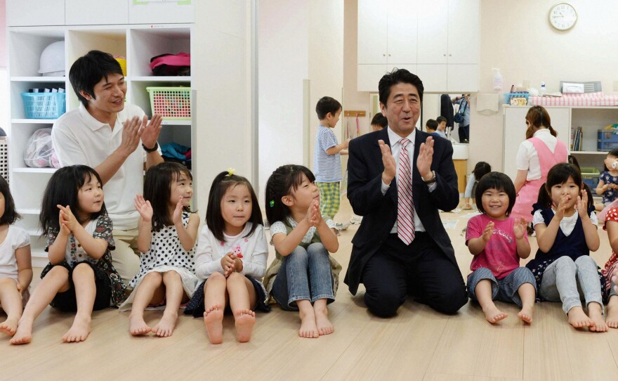 Japan's Prime Minister Shinzo Abe plays with children as he inspects a day care center in Yokohama in 2013. More than 20,000 Japanese children are on wait lists for day care.