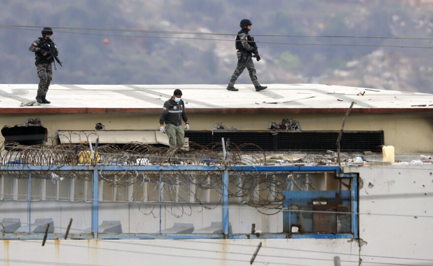 Police walk on the roof of the Litoral Penitentiary on Saturday after riots broke out inside the jail in Guayaquil, Ecuador.