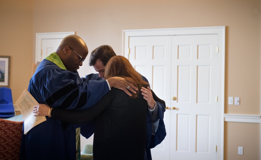Burke prays with the Rev. Bernard R. Wilson and Sandy Kinseley before delivering a sermon.