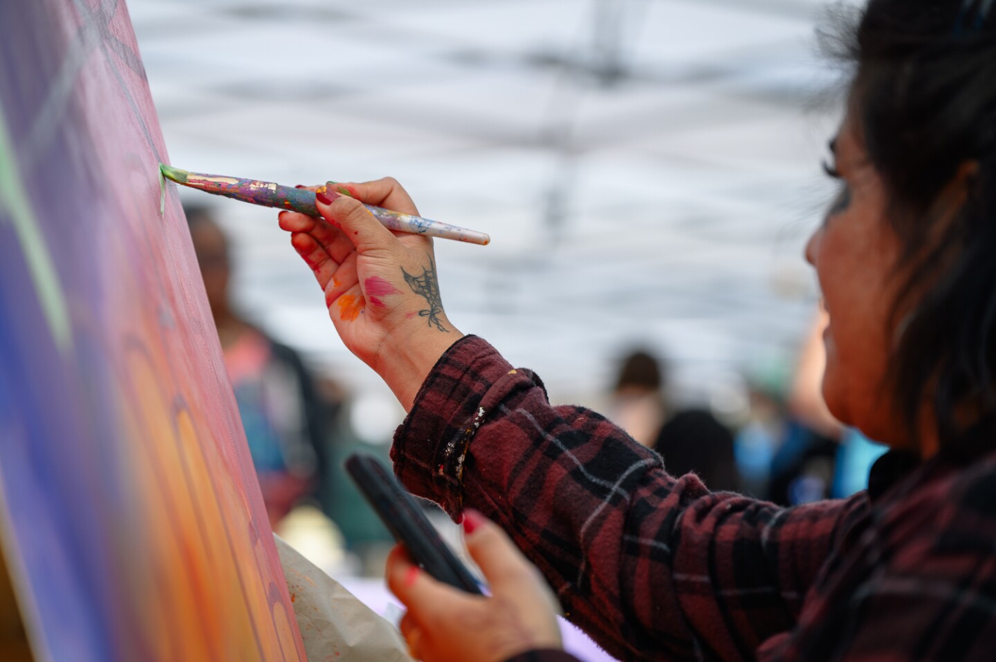 Painter Isabel Garcia, 25, adds a stroke of green to her painting during the inaugural Chula Vista Art Fest, outside Chula Vista City Hall, on Sept. 30, 2023. Garcia was one of four painters asked to perform a live painting during the festival.