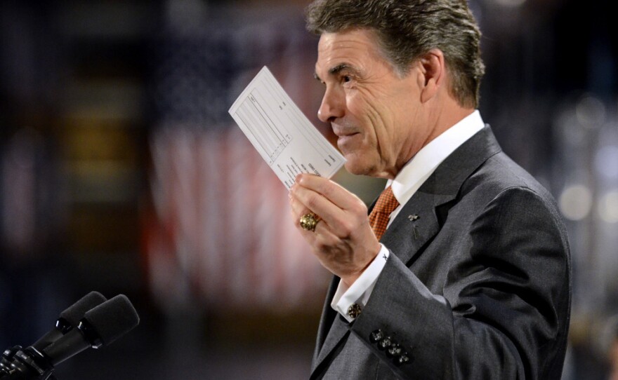 <p>Republican presidential candidate Rick Perry holds up a postcard representing his flat tax plan Tuesday in Gray Court, S.C. Perry toured the factory and then highlighted an optional 20 percent flat tax and a deficit reduction plan. </p>