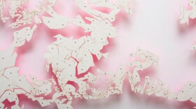 "Halo" by David Adey. Materials: Laser-cut paper, fluorescent acrylic and pins on pvc foam panel. Description: Three dimensional scan of artist’s head containing over 21k triangulated faces is unfolded and flattened in one piece. Dimensions: 36 h x 72 w x 3 1/2 inches. 2014
