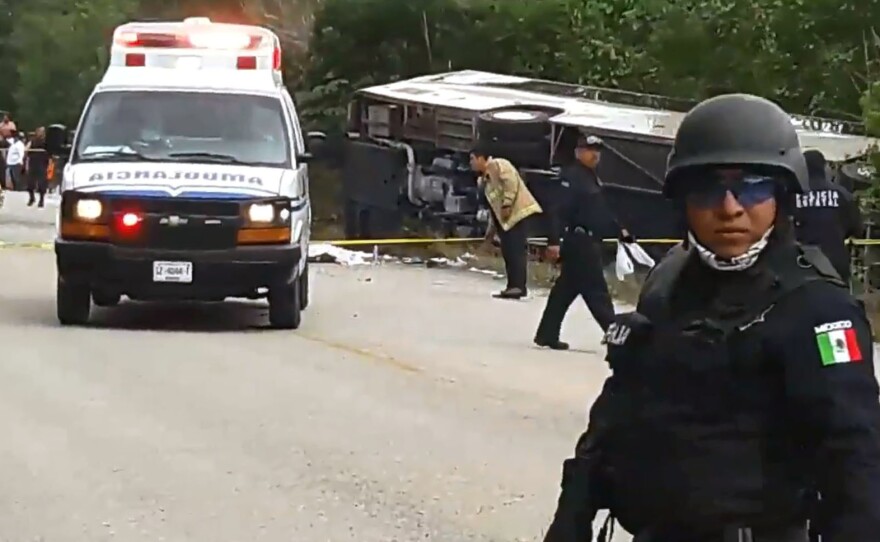 Mexican police officers stand guard near the tour bus that overturned Tuesday morning in Quintana Roo state. Twelve people were killed, including 8 Americans.