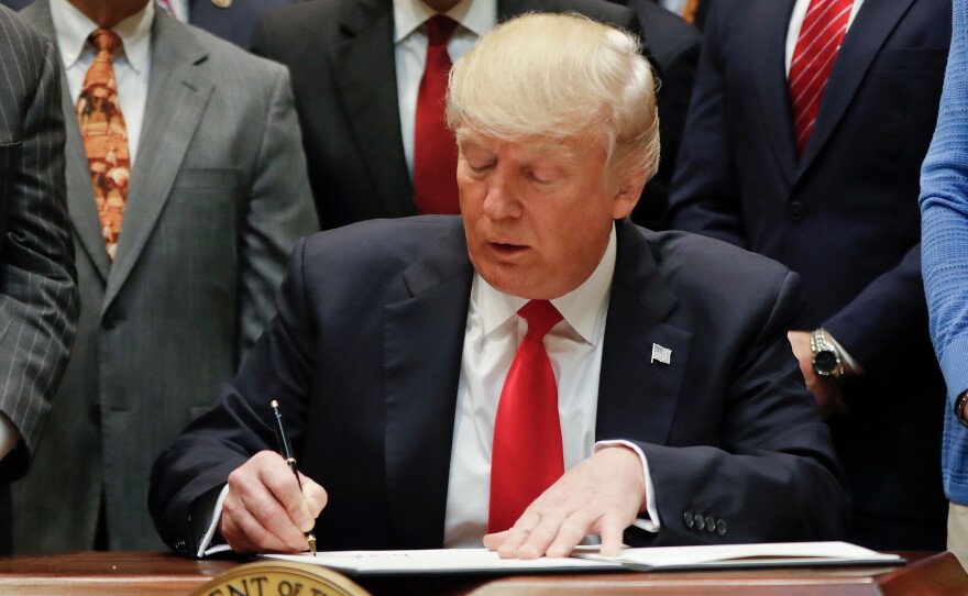 President Trump signs an executive order in the Roosevelt Room of the White House on Friday.