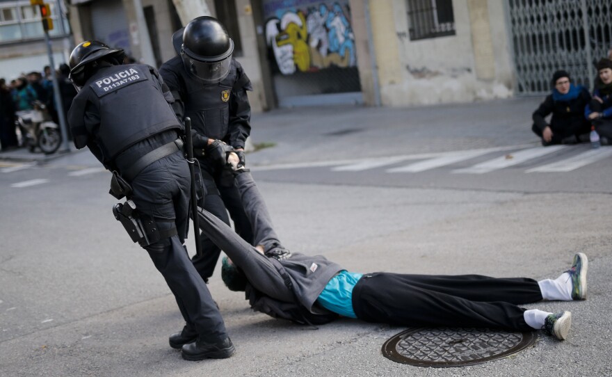 Regional police officers drag a protester from his post blocking a Barcelona street on Wednesday. The general strike, which blocked roads, highways and train tracks, ground much of Catalonia to a halt in support of the region's independence movement.