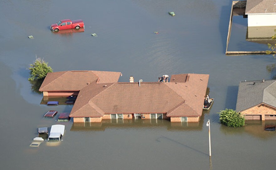 Residents of Beaumont, Texas, use a boat to get to the roof of their flooded house on Aug. 31, 2017, after the flooding caused by Hurricane Harvey.