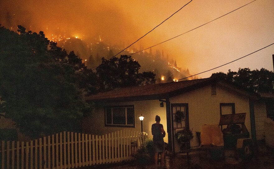 Angela Crawford walks past her home as the McKinney fire burns above it in Klamath National Forest, Calif., on Saturday.