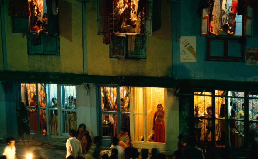 From inside their street-level cages, prostitutes try to attract potential customers: men who walk up and down the busy street sizing up each woman.