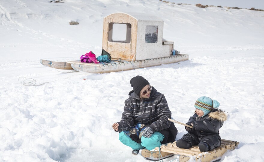 Clara Itturligaq teaches her son Spencer, who is younger than 2, how to ice fish for arctic char at Kuugarjuk Lake near Arctic Bay.
