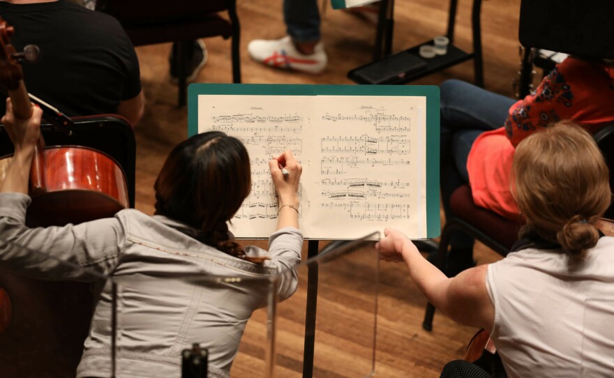 Musicians take notes during the rehearsal.