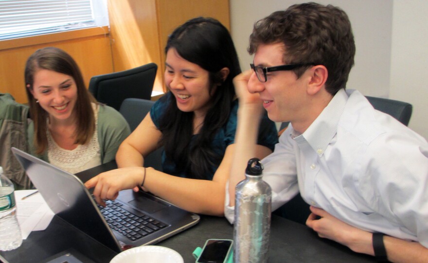 (Left to right) Students Christine Schindler, Mary Quien and Micah Timen share popcorn and a laugh during a research session. Timen worked as an accountant before medical school; his database project tracked the relative costs of a hip replacement throughout New York compared to the relative costs of a fast-food hamburger.