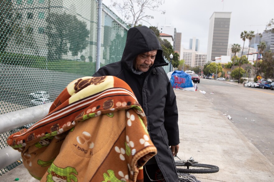 Martin Vasquez moves a blanket that was hanging to dry into his tent, San Diego, March 30, 2023.