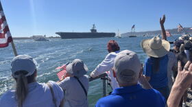 People gather with American flags along Shelter Island's shoreline ahead of the USS Lincoln's arrival, Oct. 8, 2026.