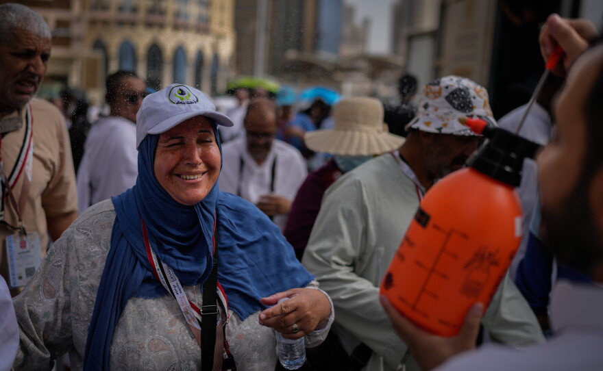 A Muslim pilgrim reacts as a volunteer sprays water to cool them outside the Grand Mosque during the annual hajj pilgrimage at the holy city of Mecca, Saudi Arabia, Sunday, May 24, 2026.