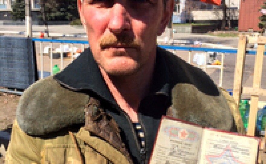 Boris Daronin is one of the activists manning the barricades in Luhansk. He holds up his ID card to show that he was in the Soviet army.