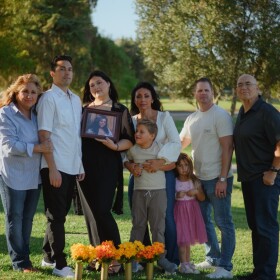 From left, Julie Estrada, Matthew Estrada, Cheyenne Estrada, Brandie Curtis, Cash Curtis, Illiana Curtis, Jeff Curtis and Larry Estrada stand for a portrait behind Ciara Estrada's grave at the Murrieta Valley Cemetery District in Murrieta, California on Oct. 4, 2025. (Kori Suzuki / KPBS)