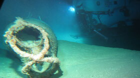 Wreck site showing the bow section and the figure-eight neck cutter with empty torpedo tubes. The research vessel is in the background. NOVA joins an exclusive dive beneath the waters of Pearl Harbor to trace new clues to the historic sinking of the USS Arizona. The discovery of a Japanese “midget sub” far from the scene of the battle raises new questions about the Arizona’s final hours. 
