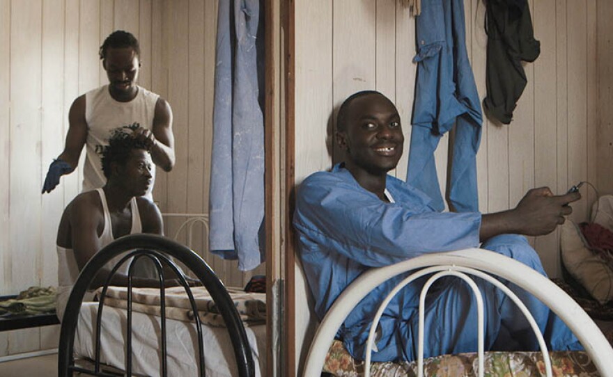 On left, Samuel from Ghana is dreading his colleague’s hair. On right, Calton from Kenya at the Um Salal camp on the outskirts of Doha, Qatar. 