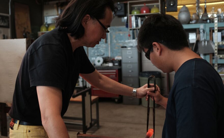Mark Mitsuda assists a student in the glassblowing studio at Punahou School, Honolulu, Hawaii.