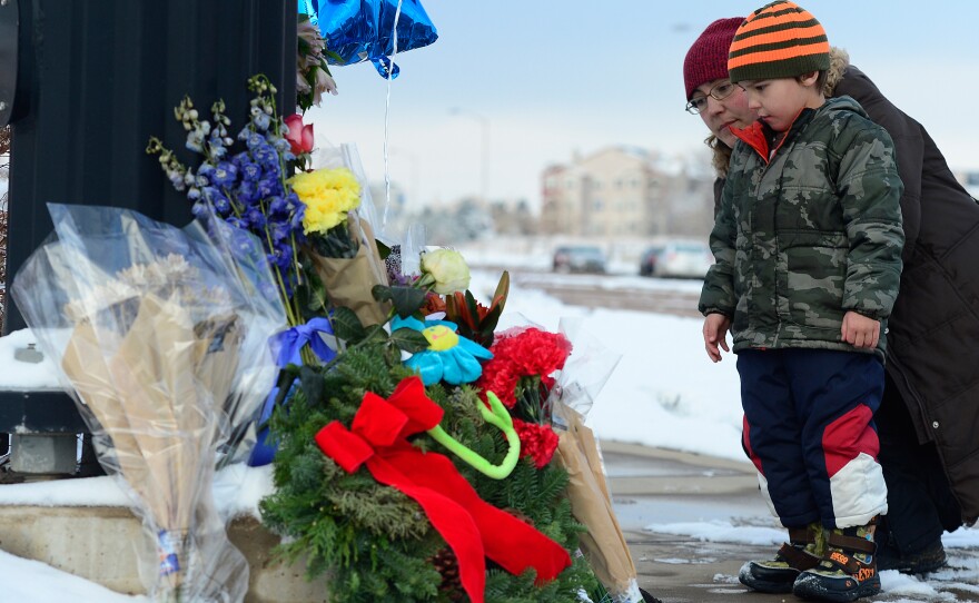Nasya Fair looks at a growing memorial for the Colorado Springs, Colo., shooting victims with her son Korbyn, 4. Colorado and California are the latest states at the center of the gun control debate.