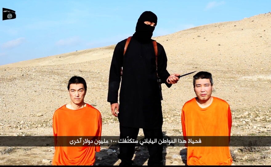 A central figure in videos released by the self-declared Islamic State has been identified as a man from West London. He's seen here dressed in black, threatening Japanese captives Haruna Yukawa (right) and Kenji Goto Jogo.