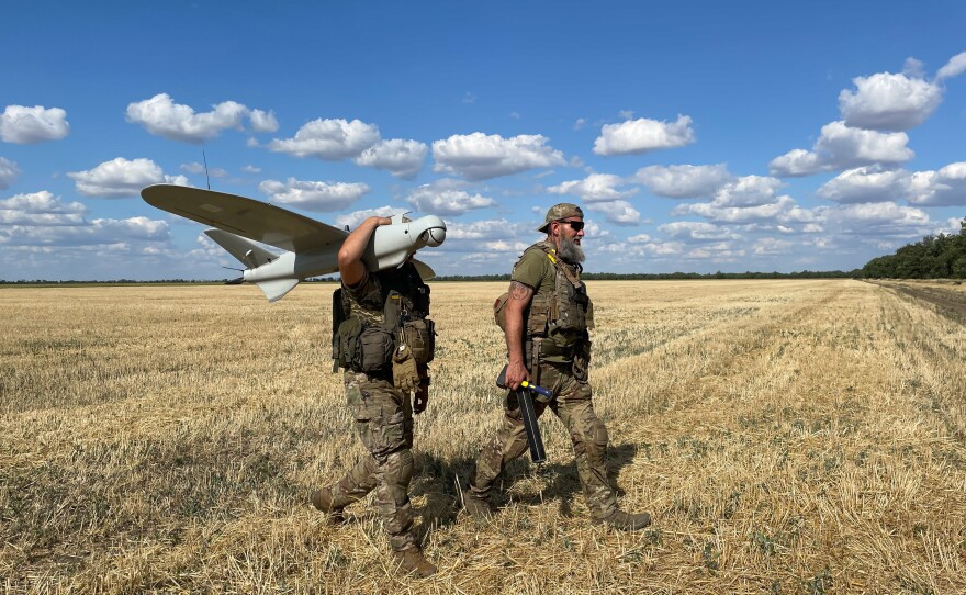 Members of the Karlson drone unit collect one of their drones that just landed in a wheat field.