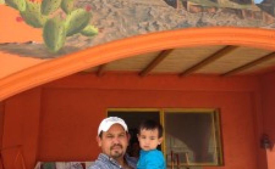 Lifetime Boquillas resident Ventura Falcon poses with his 1-year old son outside of the family restaurant.