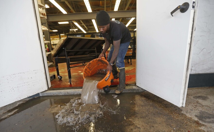 Dwayne Boudreaux Jr., owner of the Circle Food Store in New Orleans, dumps out dirty water that was vacuumed up from the store on Monday, after severe flooding over the weekend. The city's pumps were not fully functional, officials now acknowledge. Boudreaux told a local news station that the last time he saw waters rise so high was during Hurricane Katrina.