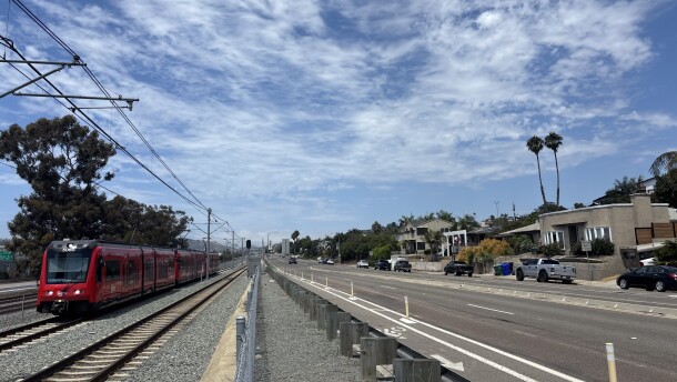 A Blue Line trolley passes by single-family homes in Bay Park, Aug. 25, 2025.