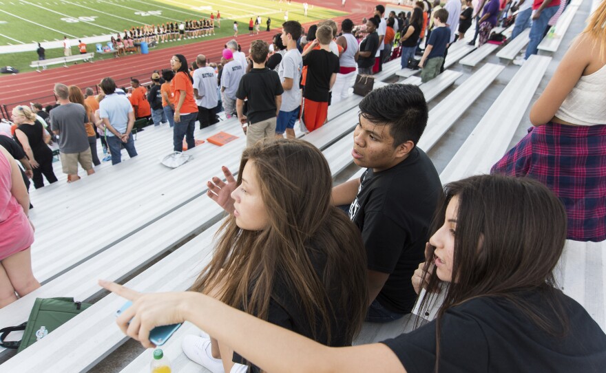 Jose and his friends Giovana Flores (left) and Anahi Macias sit and wait for the first home football game of the season to kickoff at S.E. Williams Stadium in Tulsa, Okla. All three students recently started their freshman year at Booker T. Washington High School.