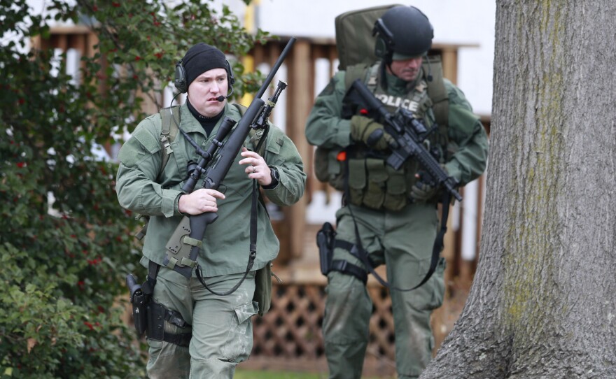 Police move near a home in Souderton, Pa., Monday, as they search for a suspect in the shooting deaths of six people.