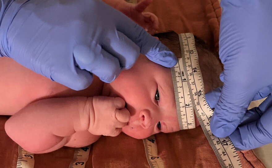 A midwife measures Willow's head after she was born at home, Oct. 2022.