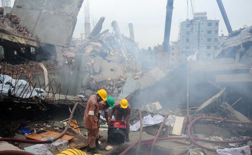 On April 29, 2013, Bangladeshi firefighters try to control a blaze during a rescue attempt as Bangladeshi army personnel begin the second phase of the rescue operation following the Rana Plaza collapse.