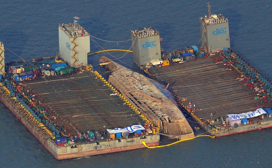 This aerial image shows part of the damaged Sewol ferry between two barges during a salvage operation Thursday.