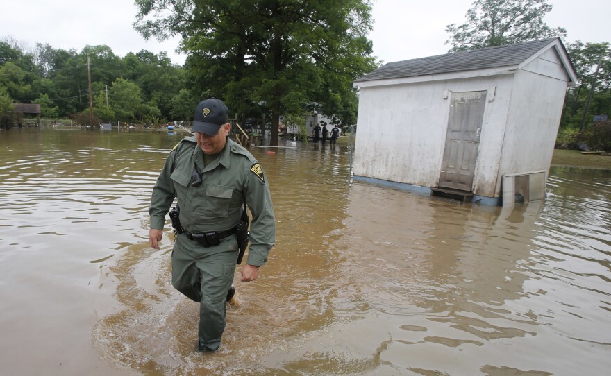 West Virginia State Trooper C.S. Hartman walks from a shed that he checked out as he and other crews search homes on Saturday in Rainelle, W. Va.