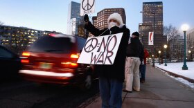 An anti-war protester stands alongside a downtown street at rush hour on Wednesday in Denver. About three dozen demonstrators gathered outside the state capitol building to protest the war, a day after President Obama announced plans to send an additional 30,000 troops to fight in Afghanistan.