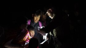 Migrants show their documents to a Border Patrol officer as they are processed after crossing the border Friday, Jan. 6, 2023, near Yuma, Arizona. The Biden administration on Thursday launched an online appointment system for migrants to be exempt from limits on seeking asylum, its latest major step in eight days to overhaul border enforcement. 