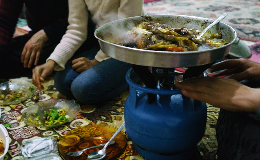 A Syrian woman cooks Aleppo-style kebab on a platter over a propane stove in her apartment in the southern Turkish city of Kilis, near the border with Syria, in December 2015.